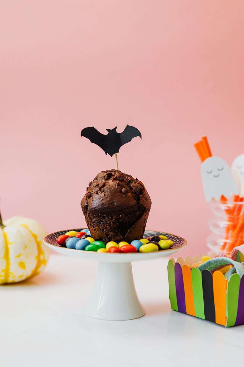 Chocolate muffin with a bat topper surrounded by candy